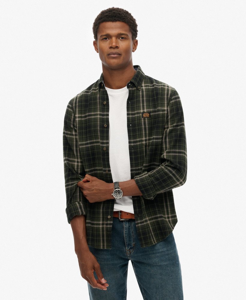 Man wearing a plaid shirt over a white t-shirt with a visible brand logo on a white background