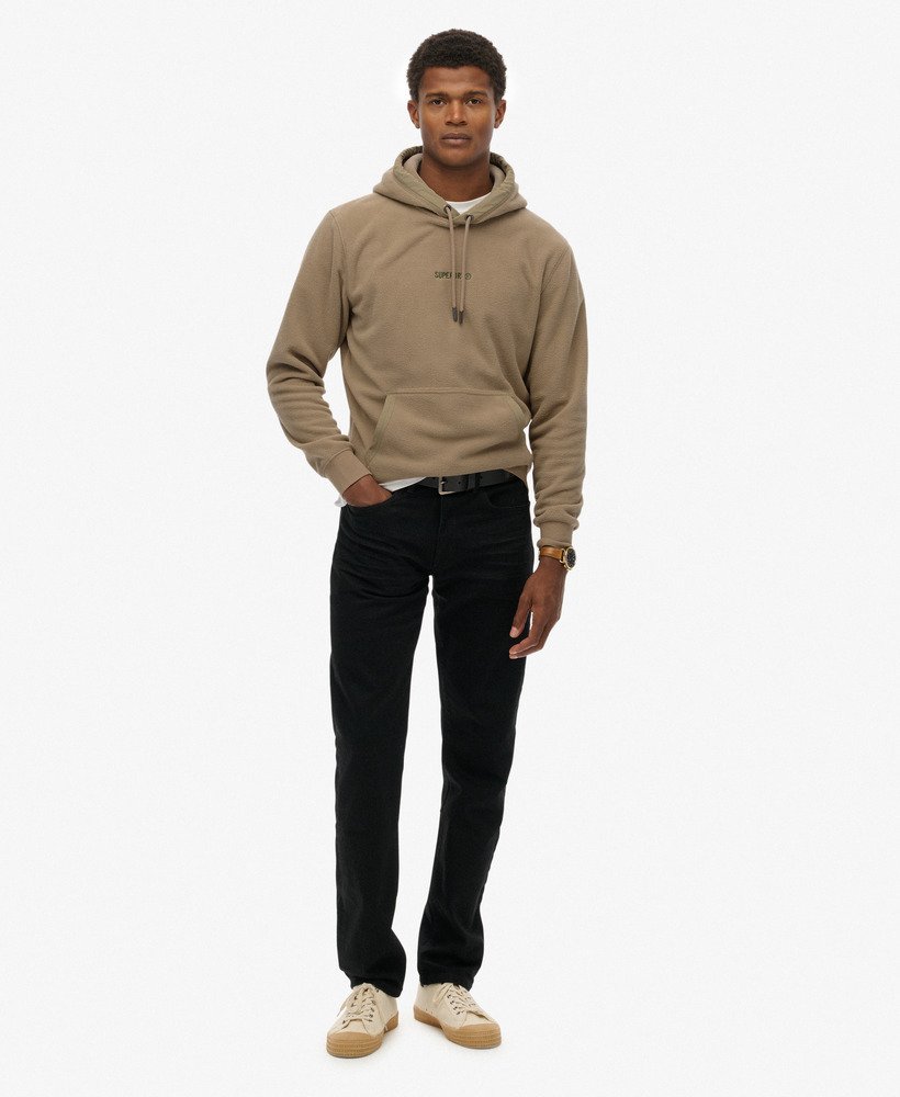 Man wearing a beige hoodie and black pants on a white background
