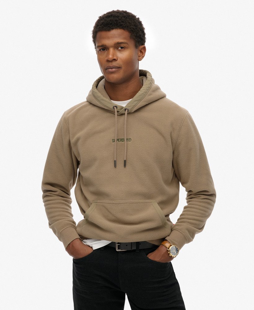 Man wearing a beige hoodie with a brand logo on a white background