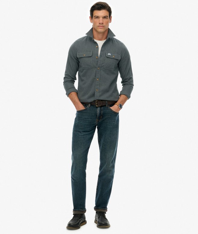 Man wearing a green flannel shirt and jeans on a white background