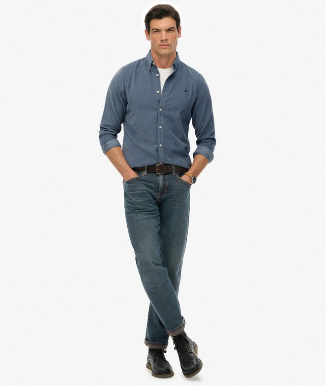 Man wearing a blue shirt and jeans on a white background