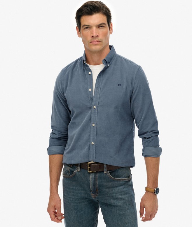 Man wearing a blue button-up shirt and jeans on a white background