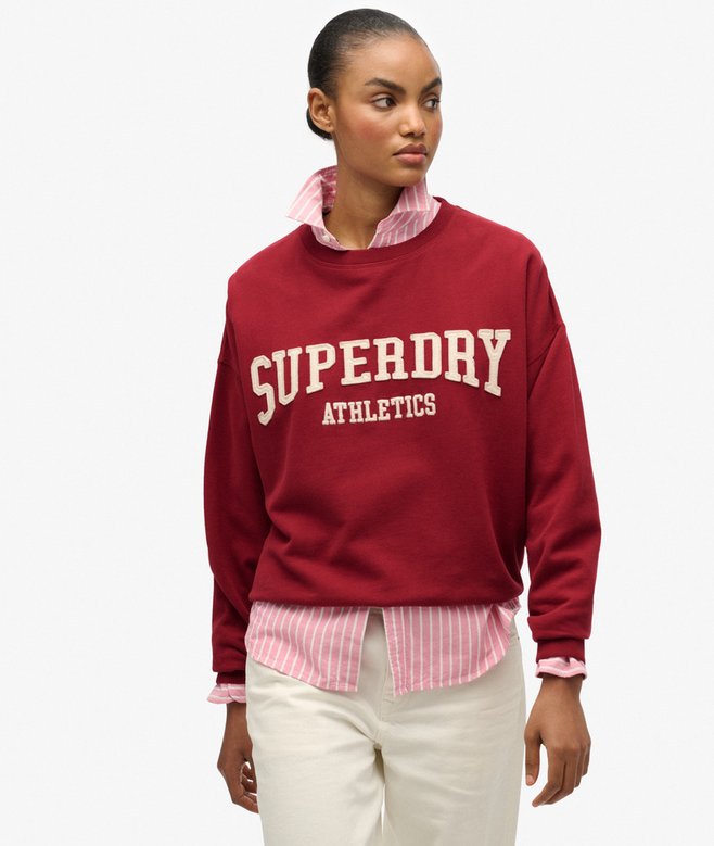 Person wearing a red Superdry Athletics sweatshirt with a white background