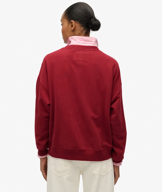 Person wearing a red sweatshirt with a pink collar on a white background