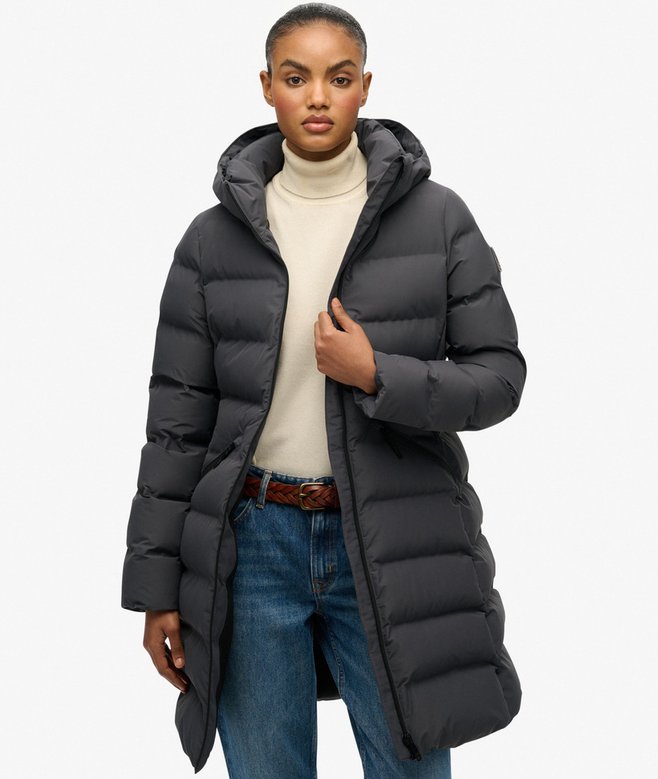 Person wearing a long black puffer coat on a white background