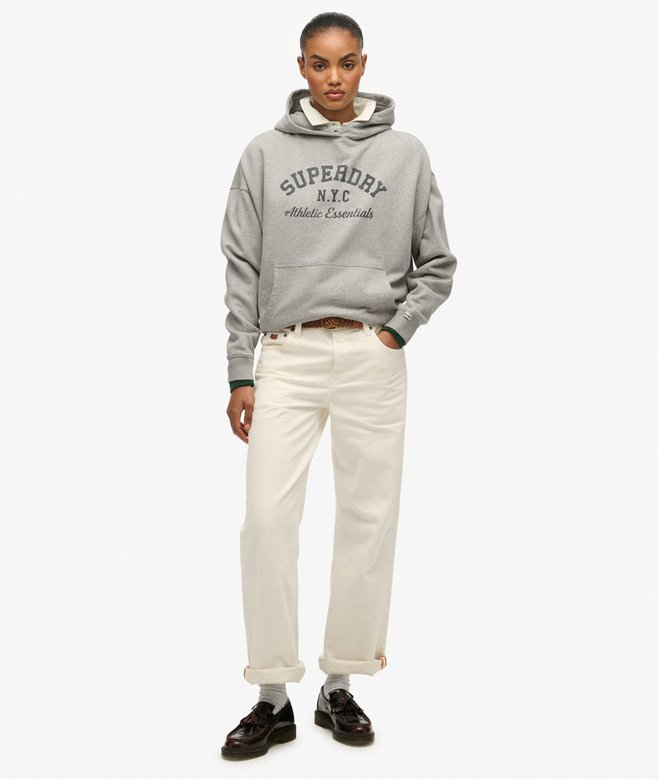 Person wearing a gray hoodie with 'Superdry' branding and white pants on a white background