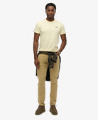 Man wearing a yellow t-shirt, plaid shirt over pants, and brown boots on a white background
