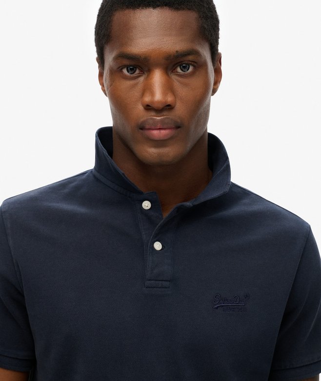 Man wearing a navy blue polo shirt with a brand logo on a white background