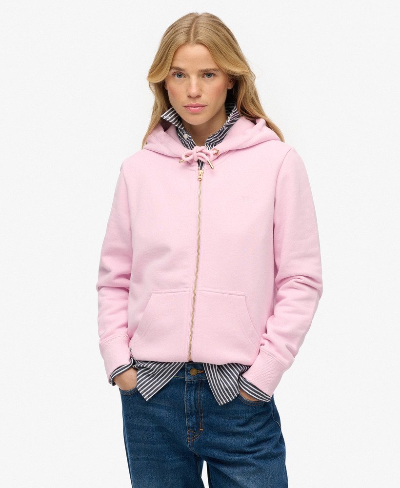 Woman wearing a pink hoodie with a striped shirt and jeans on a white background