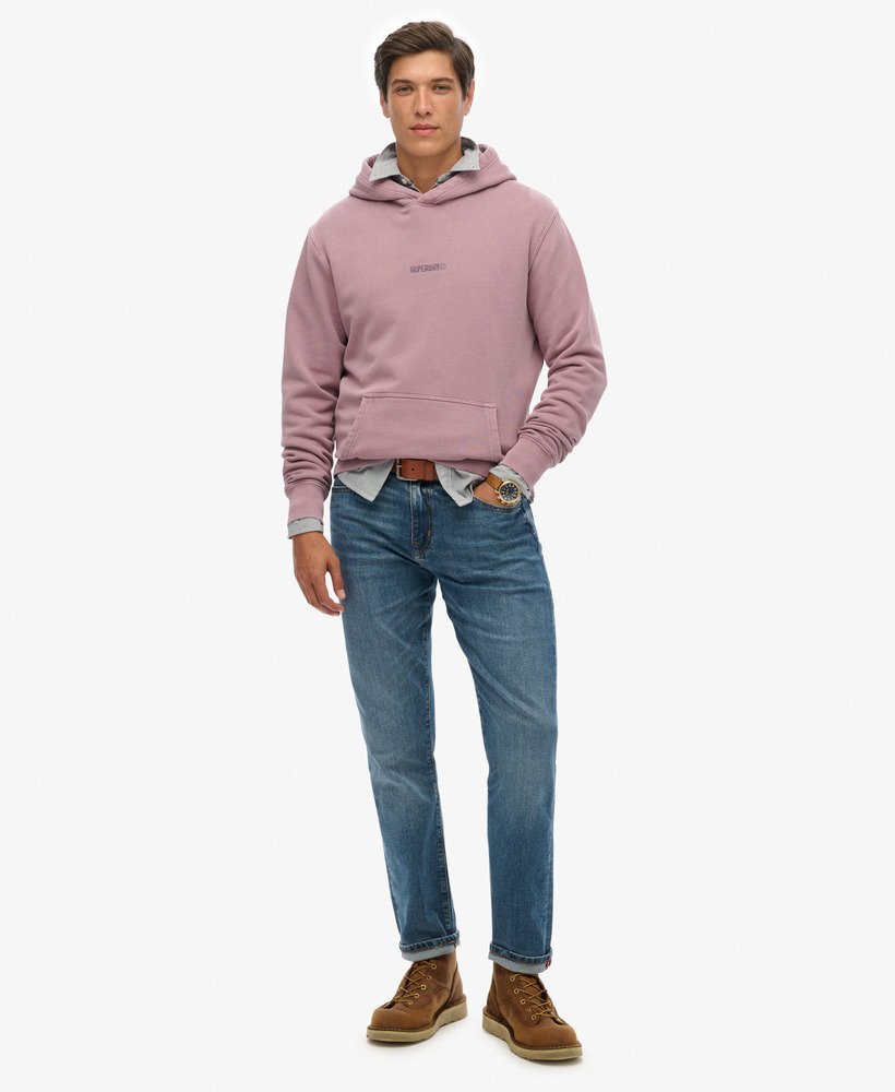 Man wearing a pink hoodie, light blue jeans, and brown boots on a white background