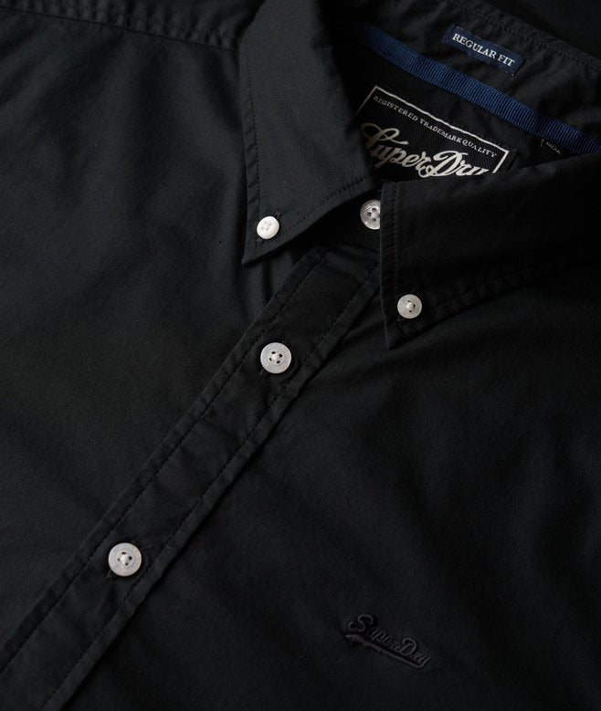 Close-up of a black jacket with Superdry branding on buttons and collar.