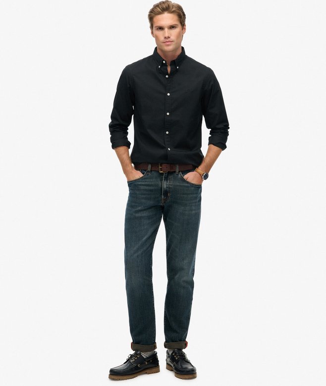 Man wearing a black shirt and blue jeans on a white background