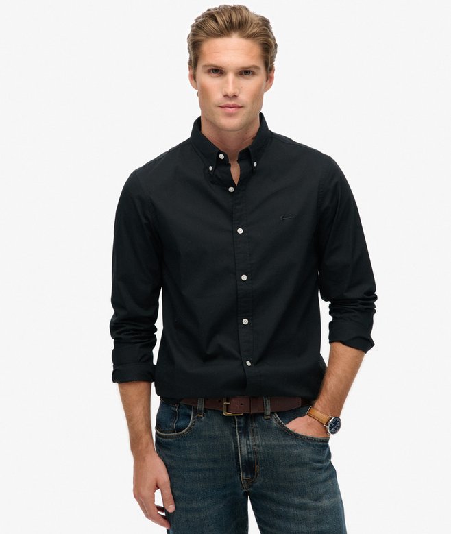 Man wearing a black button-up shirt and jeans on a white background