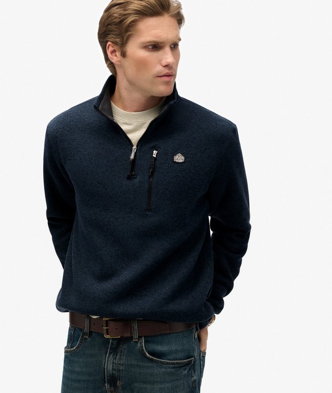 Man wearing a navy blue pullover with a logo on a white background