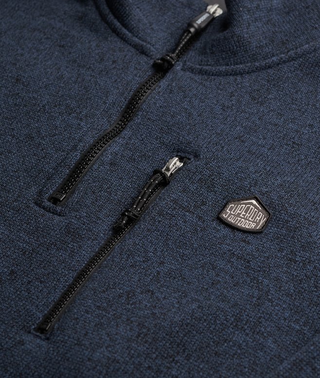 Close-up of a navy blue fleece jacket with a zipper and brand logo.