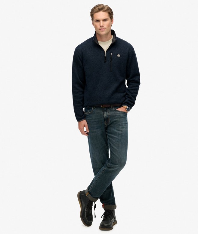 Man wearing a navy sweater and jeans on a white background