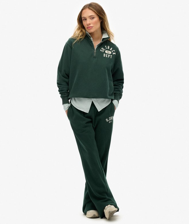 Woman wearing a green tracksuit with visible branding on a white background