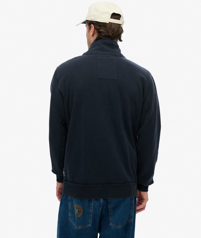Person wearing a navy blue sweatshirt and blue jeans on a white background