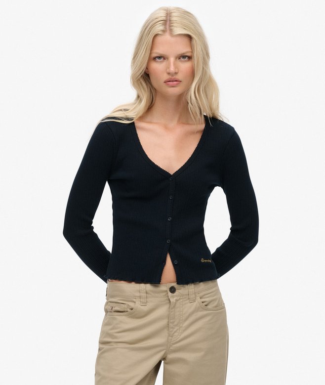 Woman wearing a navy cardigan and beige pants on a white background