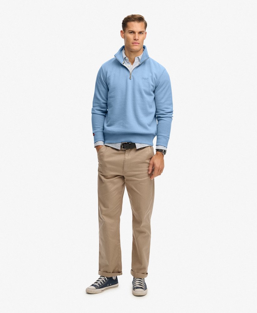 Man wearing a light blue sweater, beige pants, and black shoes on a white background