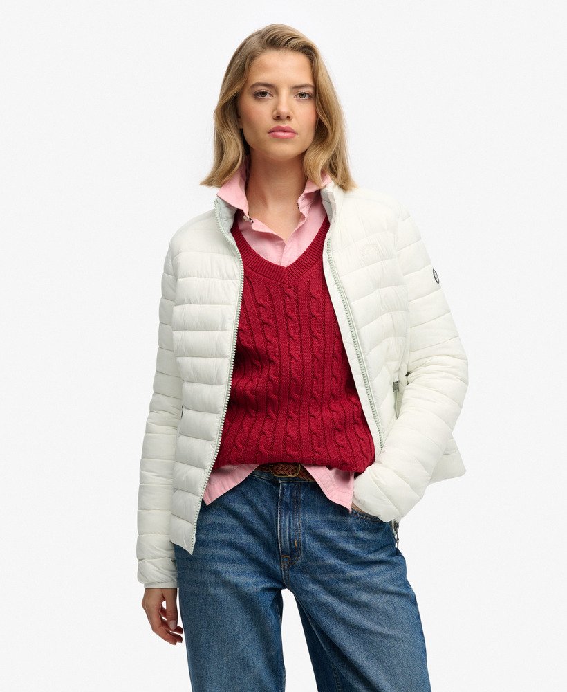 Woman wearing a white puffer jacket over a red sweater with a plain background