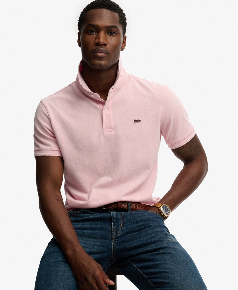 Man wearing a pink polo shirt and blue jeans on a white background
