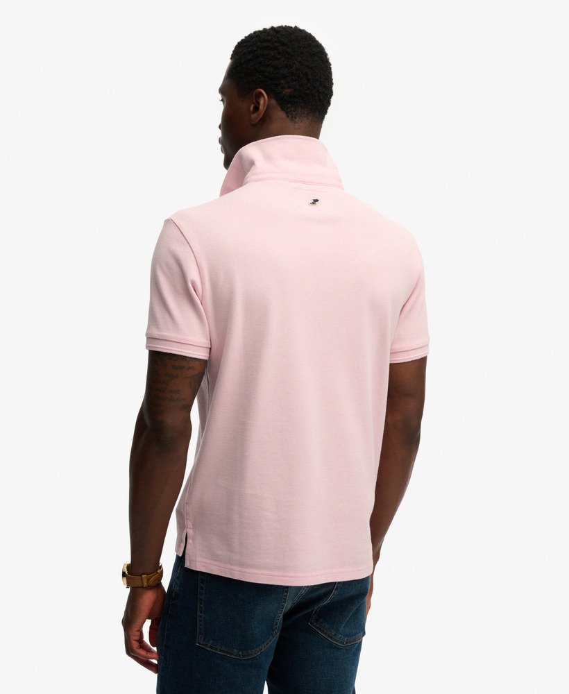 Man wearing a light pink polo shirt on a white background