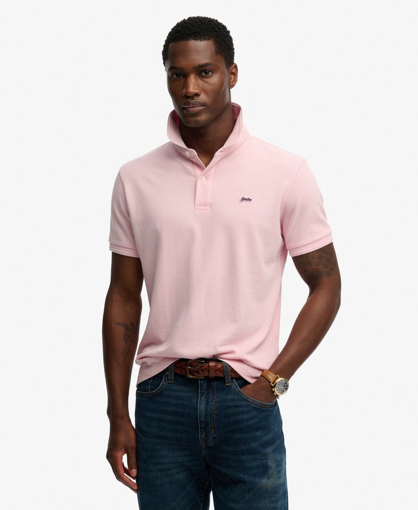 Man wearing a pink polo shirt with a brand logo on a white background