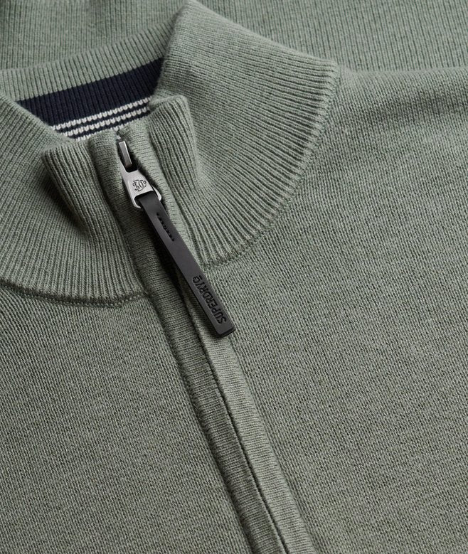 Close-up of a green sweater with a zipper and brand logo.