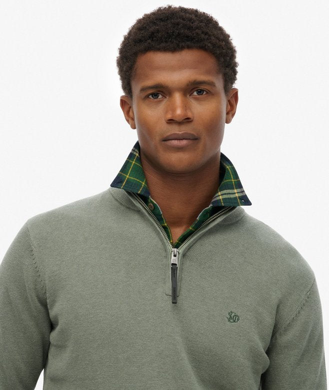 Man wearing a green sweater with a plaid collar on a white background