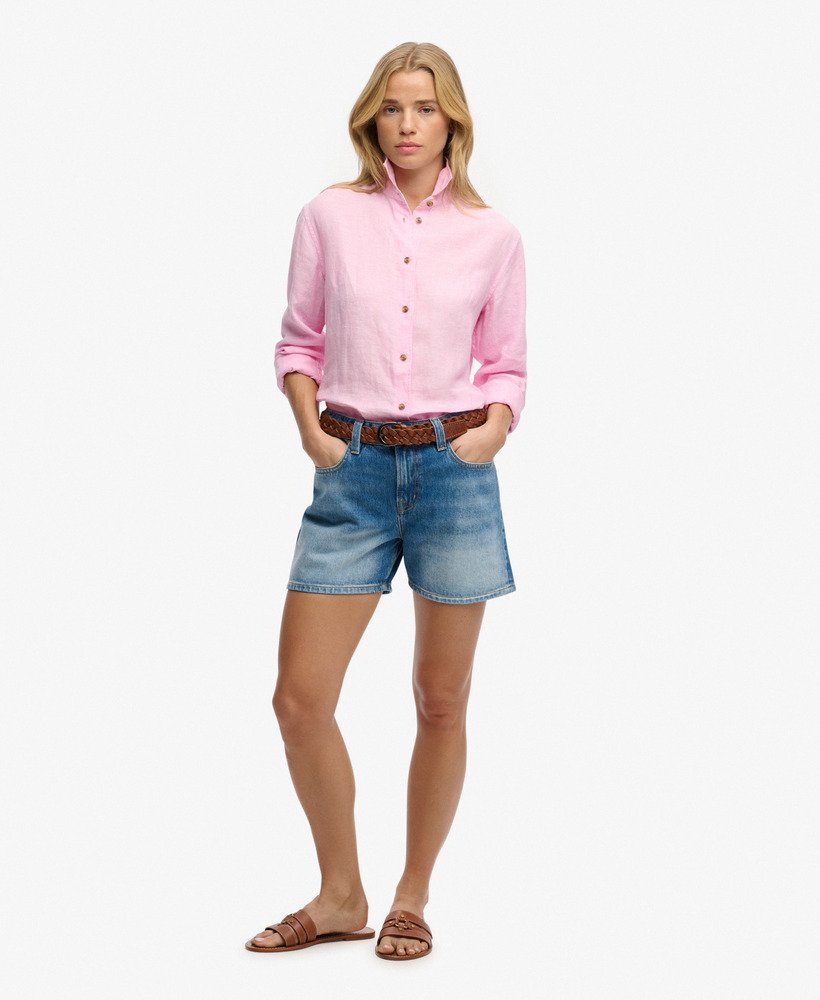 Woman wearing a pink shirt and denim shorts on a white background
