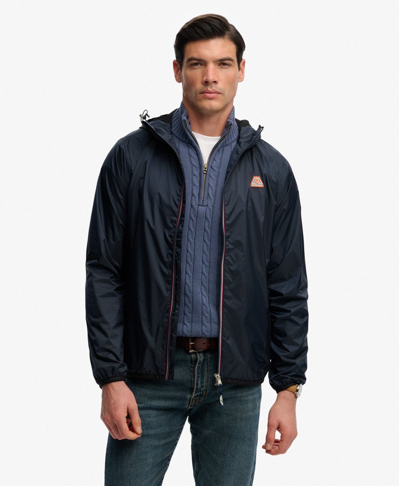 Man wearing a dark blue jacket with a brand logo on a white background