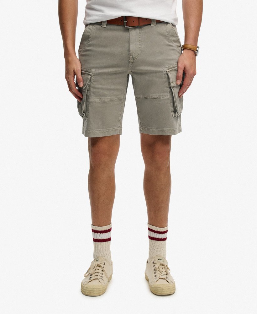 Person wearing beige cargo shorts on a white background