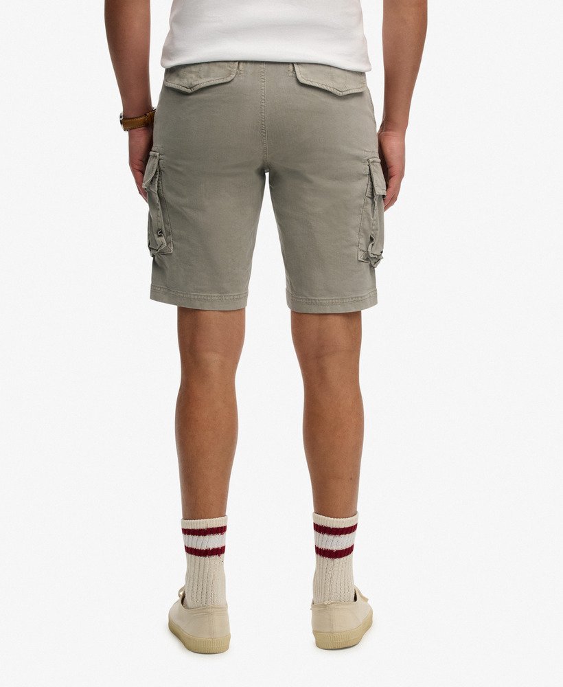 Person wearing beige cargo shorts on a white background