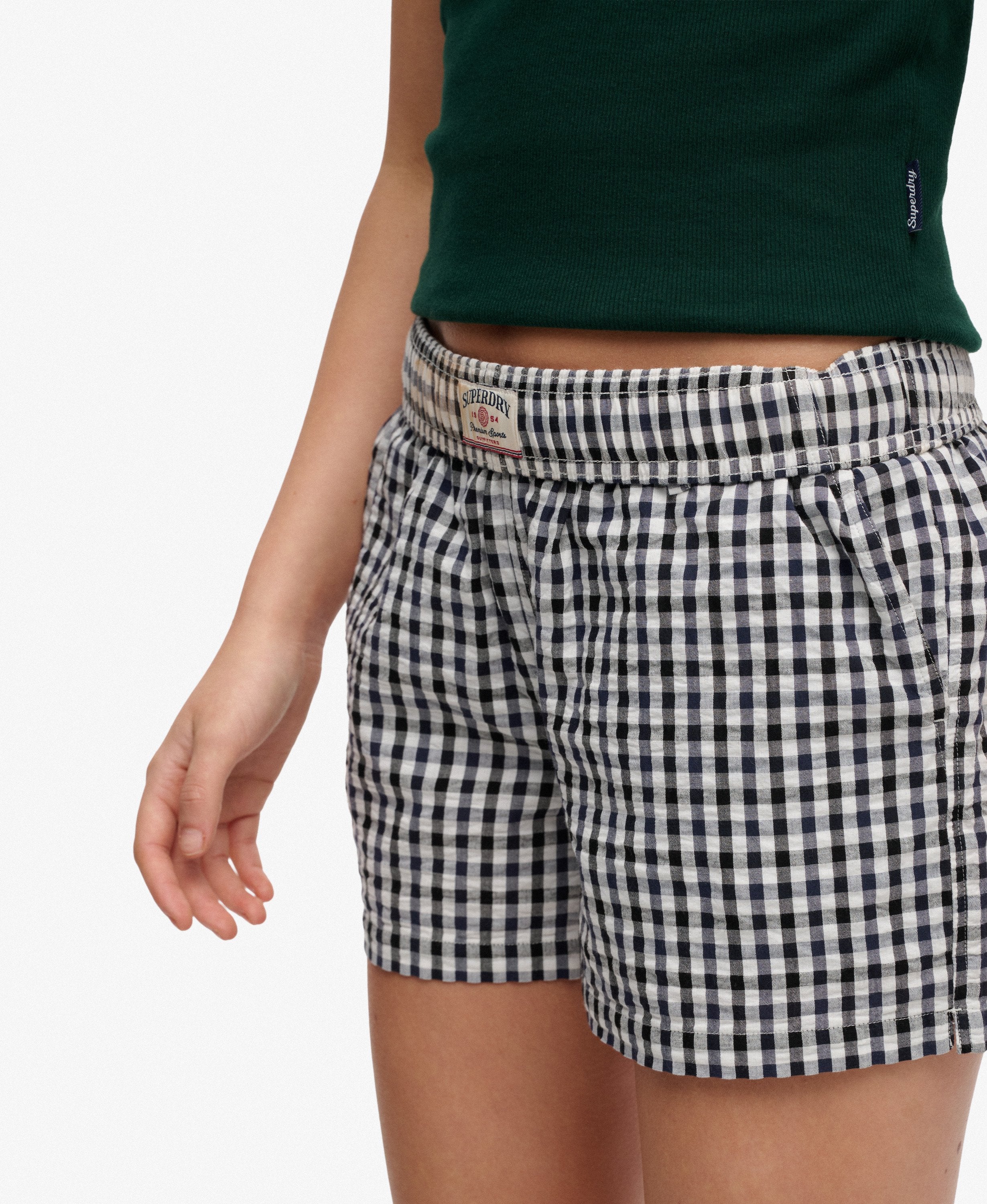 Person wearing black and white checkered shorts with a green top on a white background