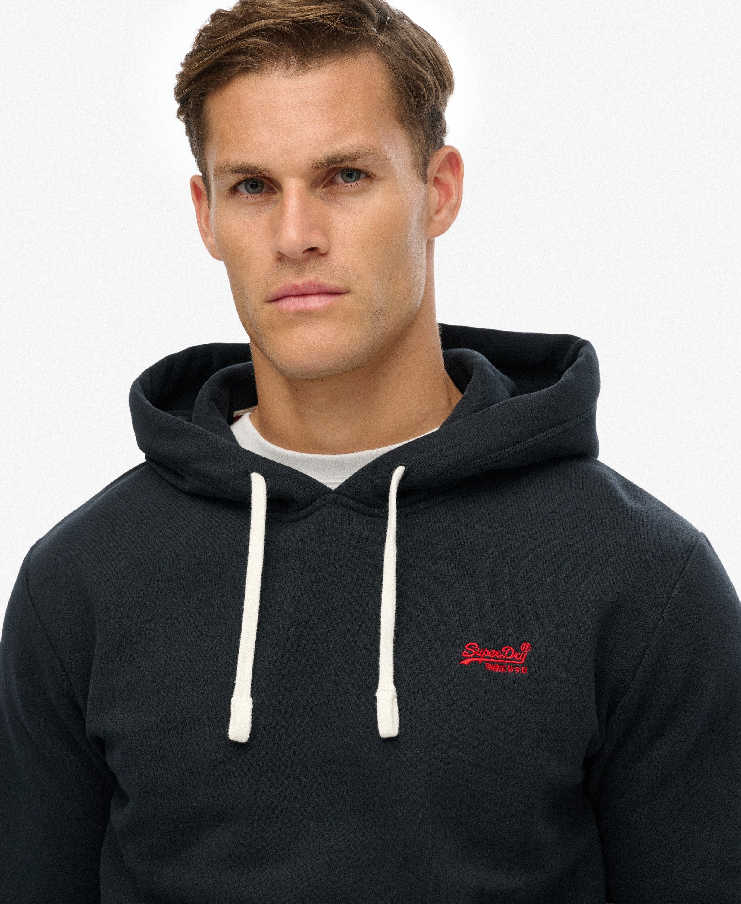 Man wearing a black hoodie with a red logo on a white background
