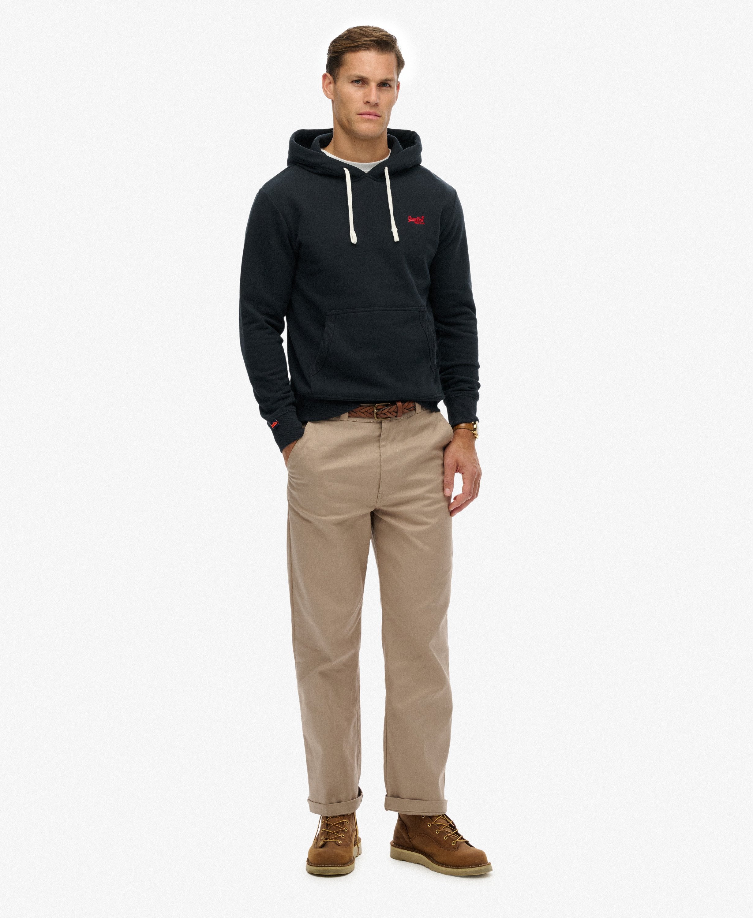 Man wearing a black hoodie with a logo, beige pants, and brown boots on a white background