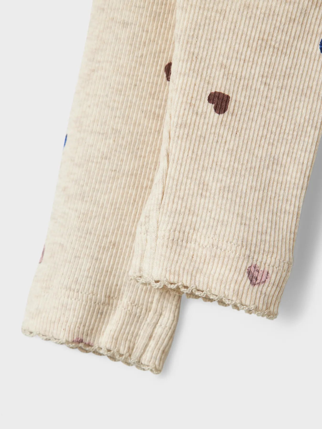 Beige legging pants with heart patterns on a white background