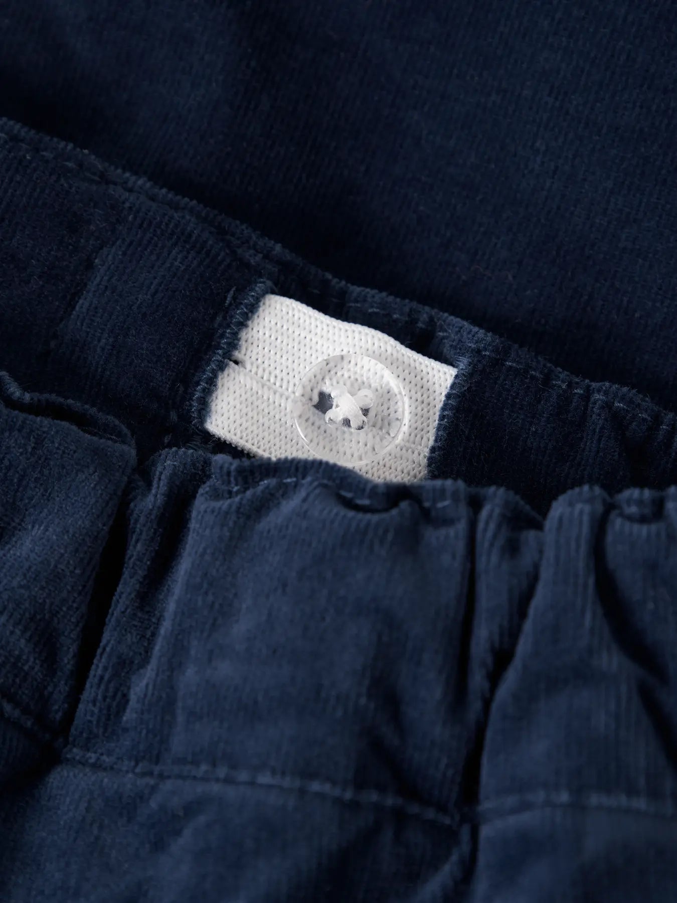 Close-up of a navy blue garment with a brand label on a dark background